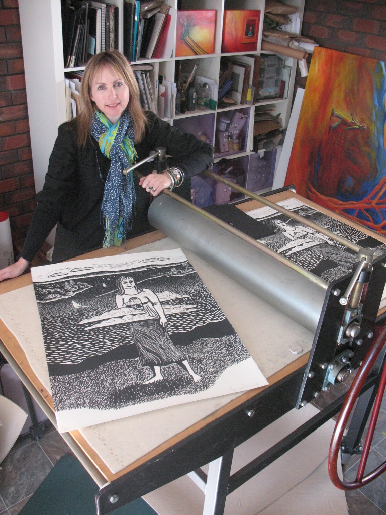 Shana at her etching press with her linocut "Thinking Differently in this Space"